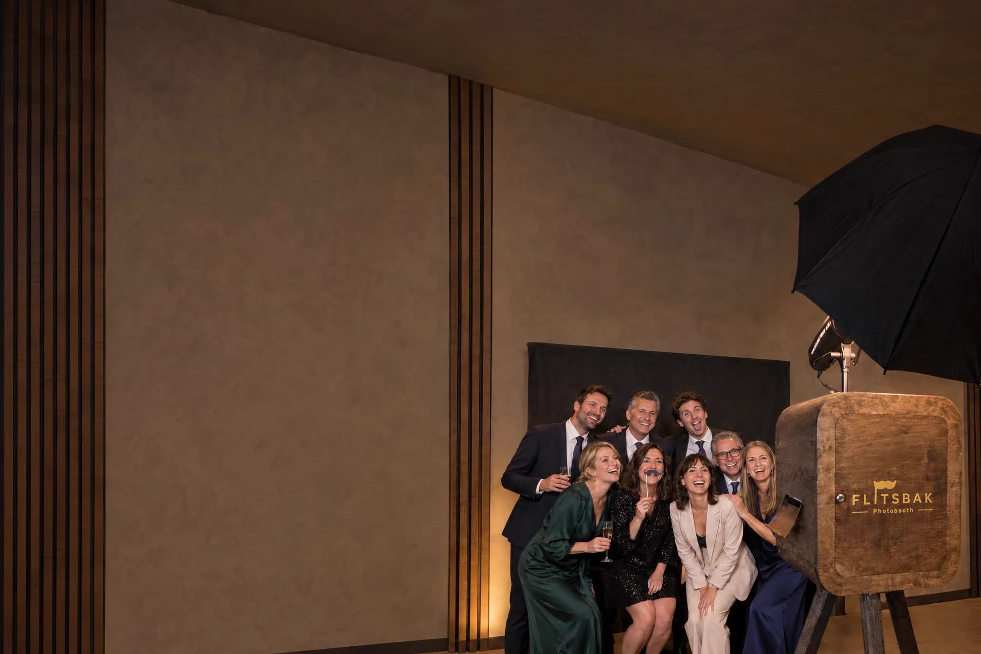 Collega's in feestkledij poseren lachend voor de Flitsbak photobooth op een eindejaarsfeest