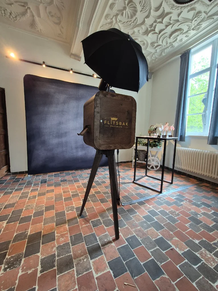 Flitsbak-photobooth voor een zwarte backdrop onder een sierlijk plafond