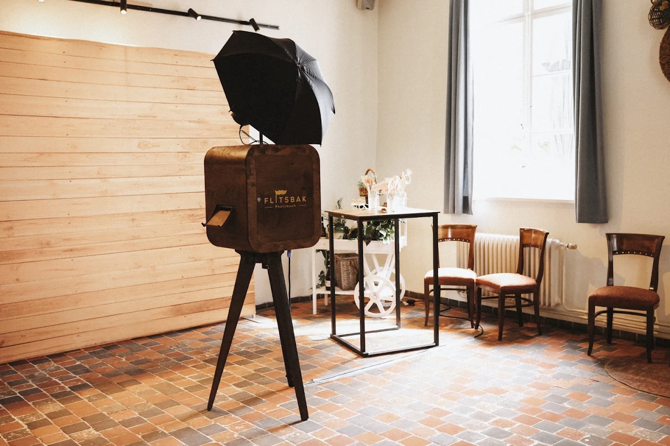 Flitsbak-photobooth in een lichte zaal met houten wand