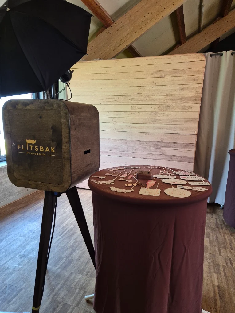 Flitsbak-photobooth met props-tafel voor een houten wand